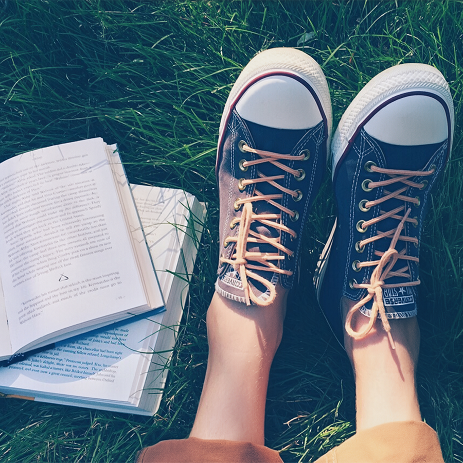 Livres posés dans l'herbe et baskets d'été