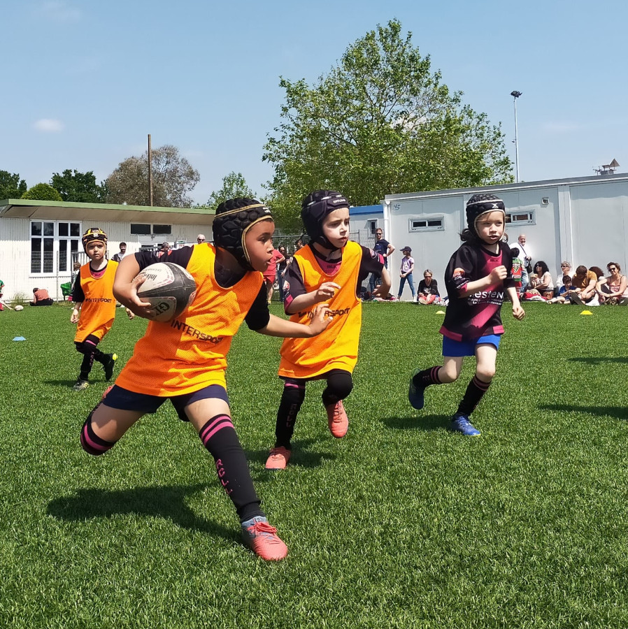 trois enfants jouant au rugby sur un terrain en exterieur