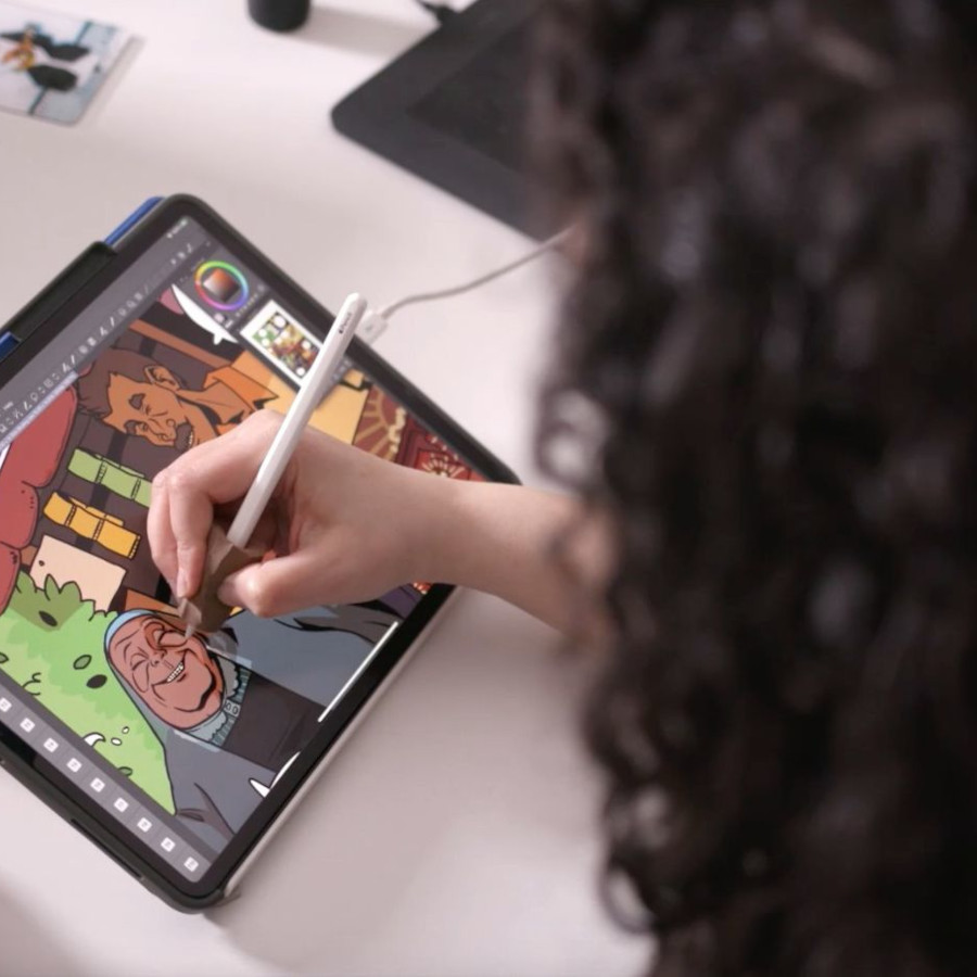 une femme de dos dessine sur une tablette graphique